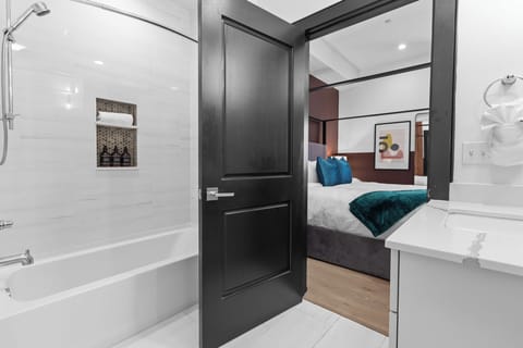The primary bathroom offers sleek finishes, a soaking tub with Smart TV, walk-in shower, and plush towels. Spacious and private, it adds a luxurious touch to your suite—perfect for unwinding after a day in Downtown New Orleans.