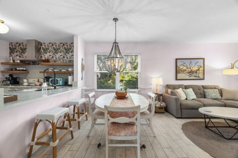 Charming dining space with elegant chandelier, seating for six (and extenders for more), open kitchen with bar for seating, and warm natural light.