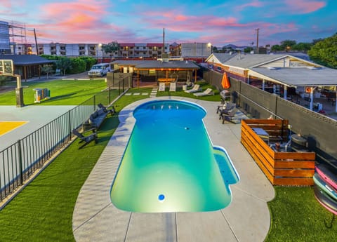 Sunset by the pool—watch the sky glow pink and blue as you slip into the water, with grassy space and lounge seating nearby for post-swim lounging.