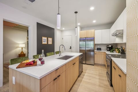 Fully equipped modern kitchen stocked with all culinary essentials and featuring brand new stainless steel appliances with an island offering bar seating.