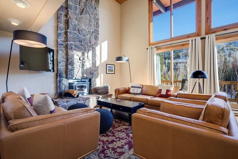 Sink into plush leather seating by your crackling fireplace, where floor-to-ceiling windows frame stunning mountain views in this beautifully appointed living space.