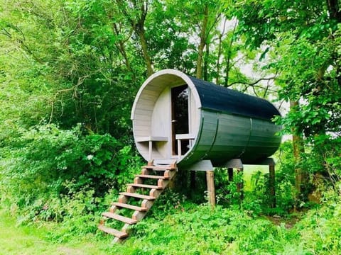 A cozy barrel-style treehouse perched above the grass. Step up into your own woodland hideaway and leave the world behind.