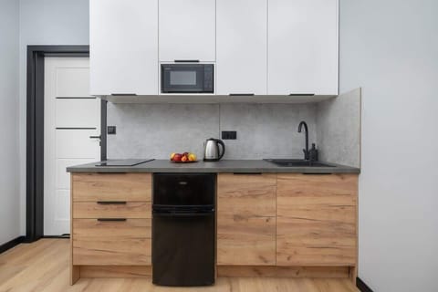A small kitchen corner with essential appliances including a coffee machine and microwave. Sleek black and wood finish.
