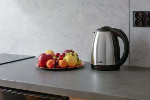 A countertop with fruit and a kettle placed neatly beside the sink. A welcoming and homely detail.

