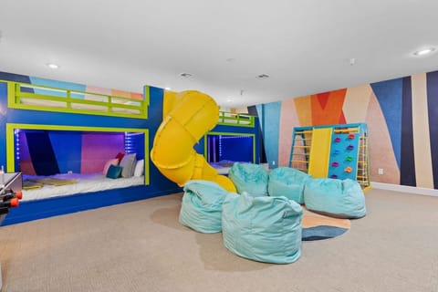 A fun bedroom with 4 queen bunk beds, slide, air hockey and climbing wall and a TV—perfect for relaxing after a day of adventure! | The Juniper, Brian Head, Utah | Voyax Luxury Vacation Rentals