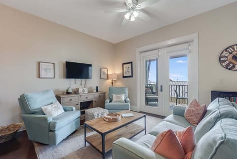 - Soft sofa and blue accent chairs offer a cozy, coastal inspired space to relax or gather - French doors fill the room with natural light and lead out to the private balcony - Wall mounted TV and side console provide stylish, easy entertainment