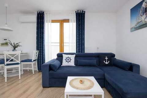A bright living room with a navy-blue sofa and white accents creates a cozy space to unwind after a day by the sea.