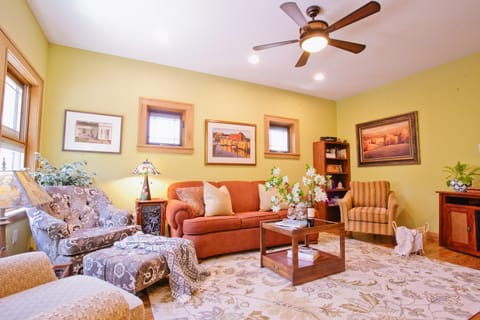 Sunlit main-level living area with plush seating, ceiling fan, and flat-screen TV—ideal for relaxing evenings after exploring downtown Black Mountain.