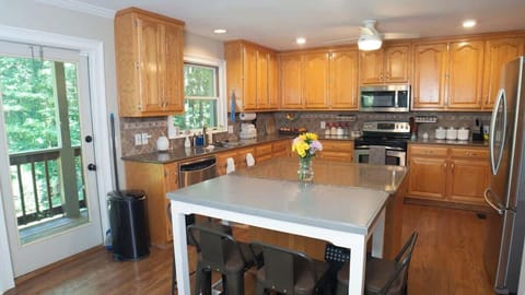 Fully stocked kitchen and leads to deck area outside overlooking backyard.
