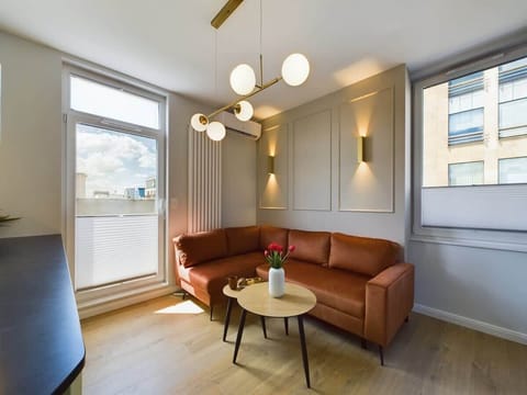 Living area with elegant round table, modern chandelier, and caramel leather sofa – cozy and stylish atmosphere.