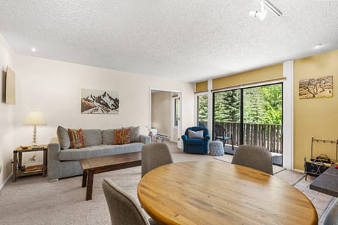 The living space with natural light and comfortable furnishings creates a cozy gathering spot to soak in the peaceful, tree-lined views.