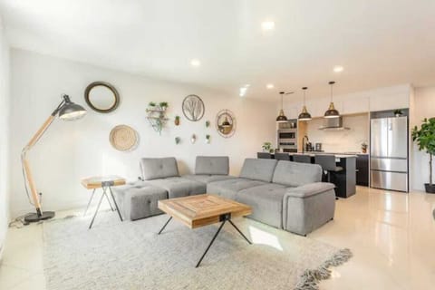 Bright, clean living area featuring a grey sofa, wooden table, and stylish wall decor.