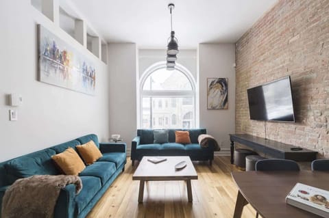 Bright living area with a striking white and brick wall combination, illuminated by a large window that fills the space with natural light.