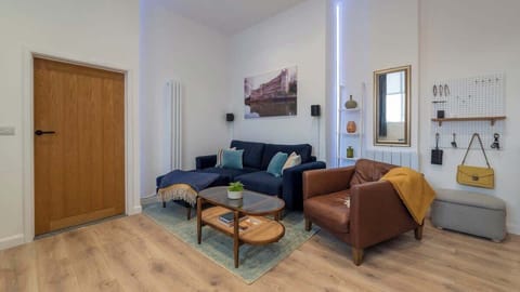 Warm, stylish, and inviting — this beautifully designed living room features a cozy navy sectional, a chic leather armchair, and a smart layout perfect for relaxing or entertaining in comfort and style.