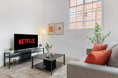 Clean and calming — a relaxing living room featuring a versatile sofa bed and a smart TV, perfect for lounging or an extra cozy sleep space.