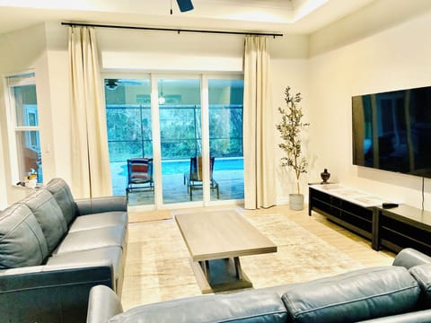 Family room with 75" TV, two couches, and large doors to the patio with a pool.