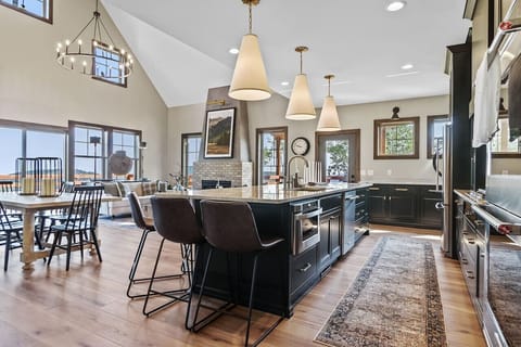 Step into a sunlit wonderland with an open living room and kitchen layout, where expansive windows create a dreamy, enchanting space perfect for magical gatherings and cozy moments.
