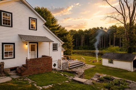 Walk out the side door and down to the fire pit for the evening, with the pond glowing behind the trees and a small deck and shed off to the side for extra storage.