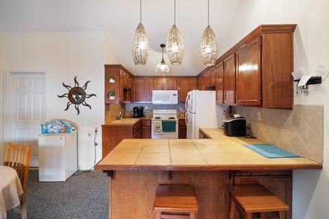 This kitchen area is warm and inviting. The overhead lighting adds a touch of elegance, creating the perfect ambiance for both casual meals and entertaining guests.