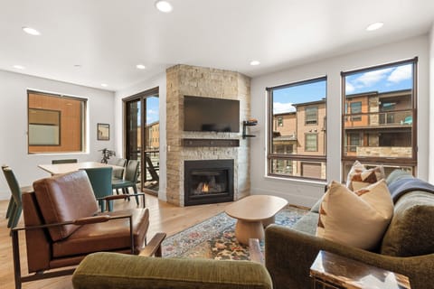Unwind in your bright living space with a cozy fireplace, stylish stone accent, and large windows framing neighborhood views—your perfect spot to relax after a day of exploring.