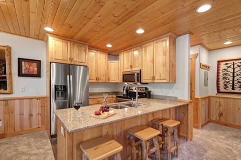 Timber Wolf Lodge 10 D's open concept kitchen with wooden cabinets, stainless steel appliances, and breakfast bar.