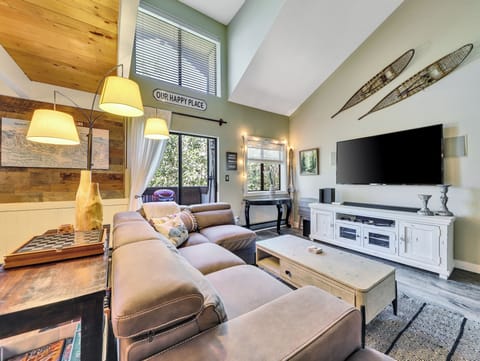 Living room with vaulted ceilings, cozy sofa, smart TV with Blu-ray player, gas fireplace, entertainment console, floor lamps, and coffee table