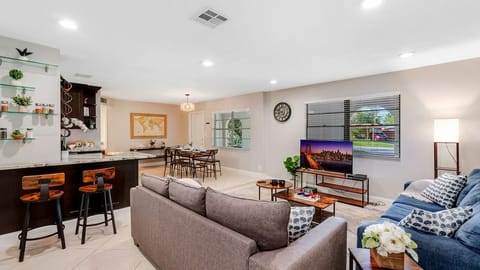 Open-concept space with dining area, sofas, coffee table, and kitchen bar.
