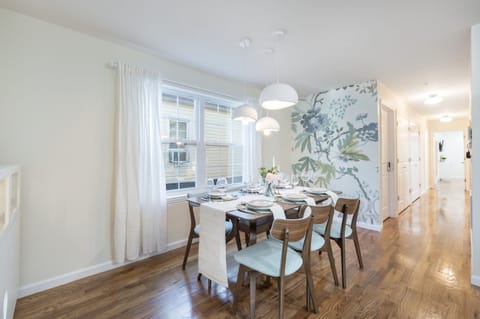 Elegant dining area with stylish table setting, floral accent wall, and modern lighting.
