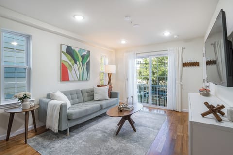 Cozy, warmly lit living room with stylish and elegant decor, smart TV, and balcony access for a relaxing vibe.