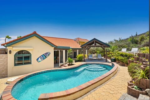 Charming villa in Tierra del Sol boasts a private pool and beautifully landscaped garden - Enjoy relaxing under the shaded gazebo with loungers - The villa's design blends modern elements, highlighted by a red-tiled roof and decorative surfboard