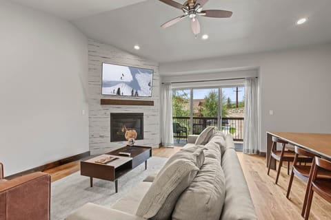 Unwind in your bright, modern living room featuring a cozy fireplace, large TV, and plush seating. Through your private balcony doors, you'll enjoy scenic views framed by natural light.