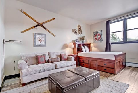 Relax in the cozy living room with comfortable seating, rustic décor, and ample natural light from large windows.