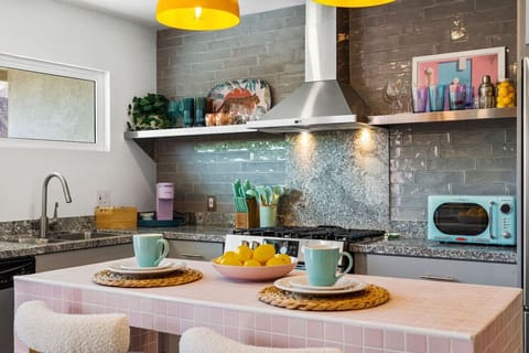 Modern kitchen corner w/ open shelving, warm lighting & space to prep & gather.
