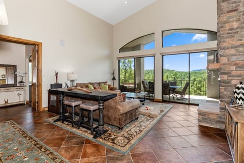 Luxury meets nature: Panoramic forest views from spacious living area. Vaulted ceilings, cozy seating, and direct balcony access. Perfect for groups. Experience Prescott's beauty at The Sanctuary. #PrescottRetreat #MountainViews #LuxuryStay