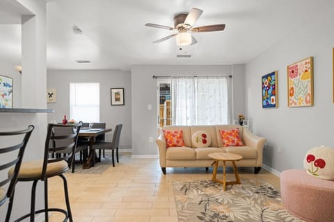 Living Room: A cozy living room with nice artwork, a brand new TV and TV stand, a comfortable sofa, and cute cushions.