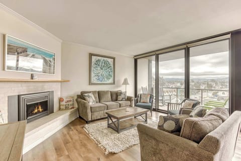 Warm and inviting living room featuring a cozy fireplace and plenty of seating wrapped by large windows allowing natural light to enter.