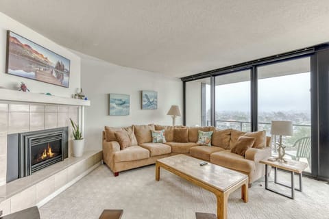 Relax in this spacious living area featuring a comfortable sectional sofa, a warm fireplace, and large windows.