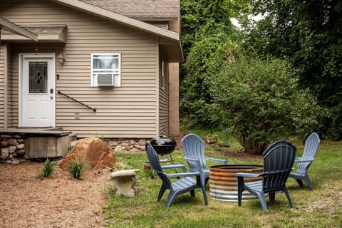 Cozy outdoor seating area w/ fire pit & Adirondack chairs, perfect for relaxing evenings under the trees.