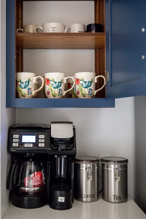 Coffee station w/ machine & colorful mugs ready for your morning brew.