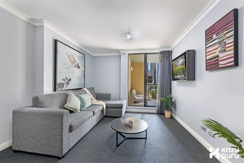 n open-plan living space showcasing a comfortable grey sectional sofa, a round coffee table, and large sliding doors leading to a balcony.