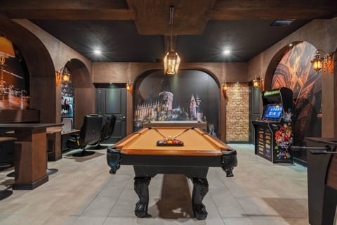 Enjoy a vibrant game room with a classic pool table, warm lighting, and rich wooden arches that create a cozy atmosphere. Retro arcade games and stylish leather seating invite you to relax and engage in friendly competition.