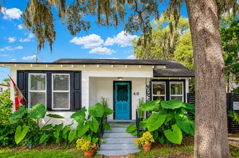 Charming tropical bungalow with bold blue door and lush shaded entry
