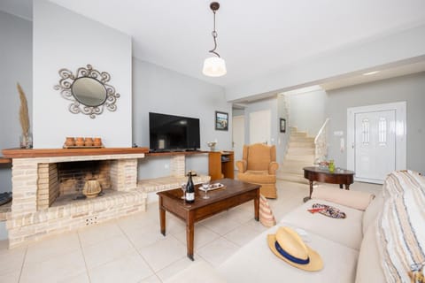 Open-plan living room with sofa, dining area, kitchen, ornamental fireplace, A/C, WiFi internet, and satellite TV