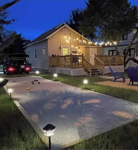 Backyard has a large deck with seating, a fire pit, corn hole, and bbq
