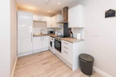 The kitchen features modern white cabinetry, stainless steel appliances, and a sleek countertop 