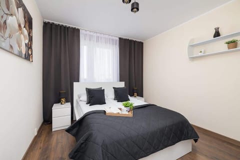 Cozy bedroom with a double bed, white furniture, and dark curtains.