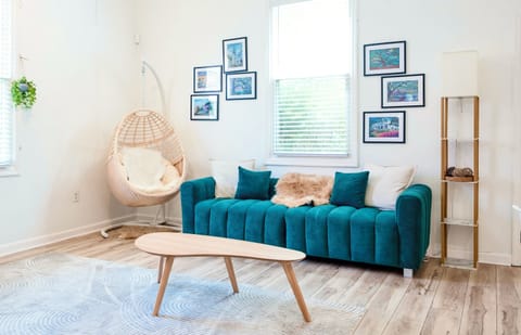 Bright living area with plush sofa and hang/swing chair and center table.
