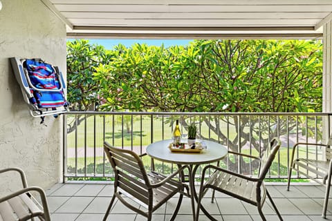 Lanai bistro set framed by lush plumeria trees.
