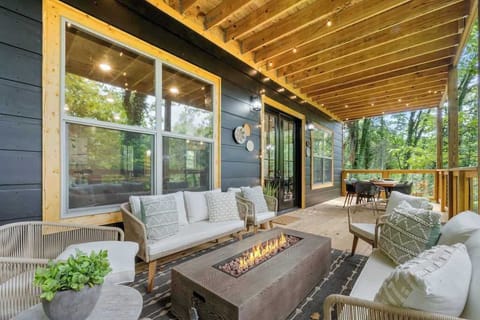 This beautifully designed outdoor space seamlessly blends style and functionality. It features a chic lounge area with modern furniture and a central fire pit that adds warmth and ambiance, perfect for evening gatherings. The adjacent dining area is ideal for al fresco meals, surrounded by the tranquil beauty of lush greenery.