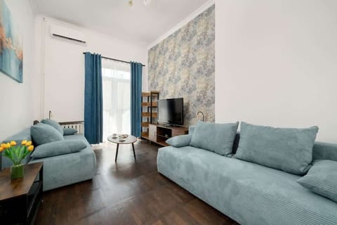 This charming bedroom is filled with soft blue furniture, floral wallpaper, and warm wooden flooring, creating a serene and cozy retreat.